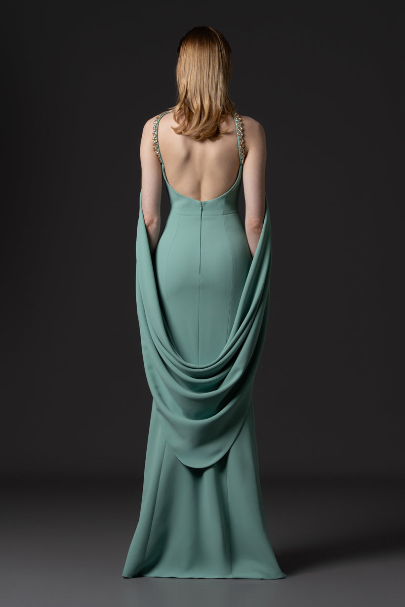 A crêpe fitted gown featuring long sweeping sleeves and beaded corset with crystals and stones