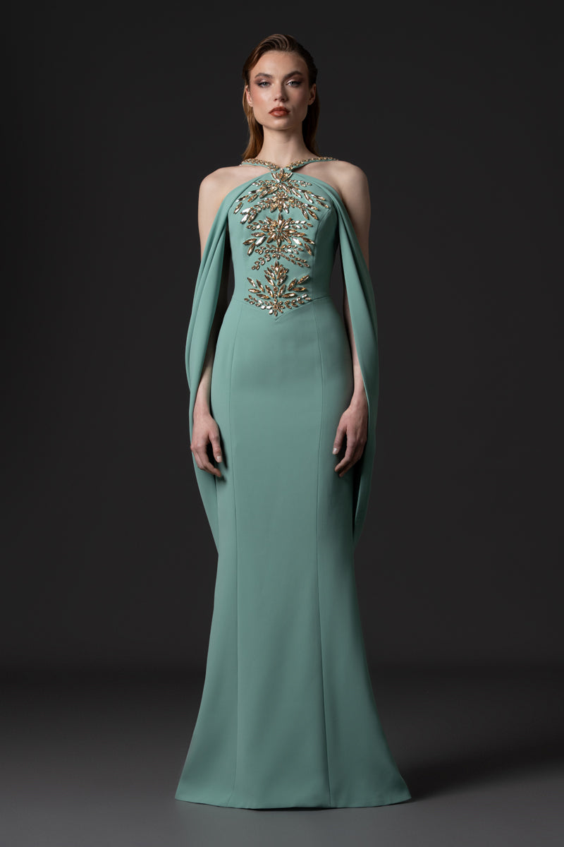 A crêpe fitted gown featuring long sweeping sleeves and beaded corset with crystals and stones
