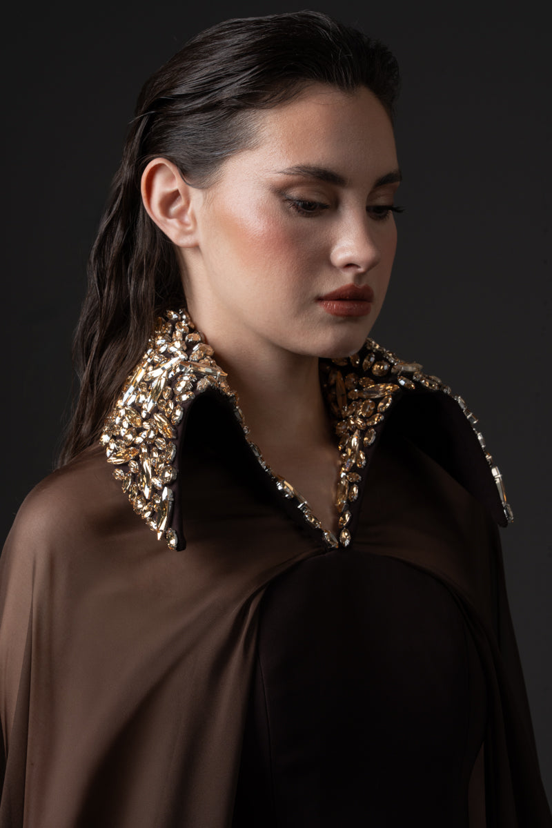 A fitted crêpe gown featuring chiffon cape and a beaded collar with crystals
