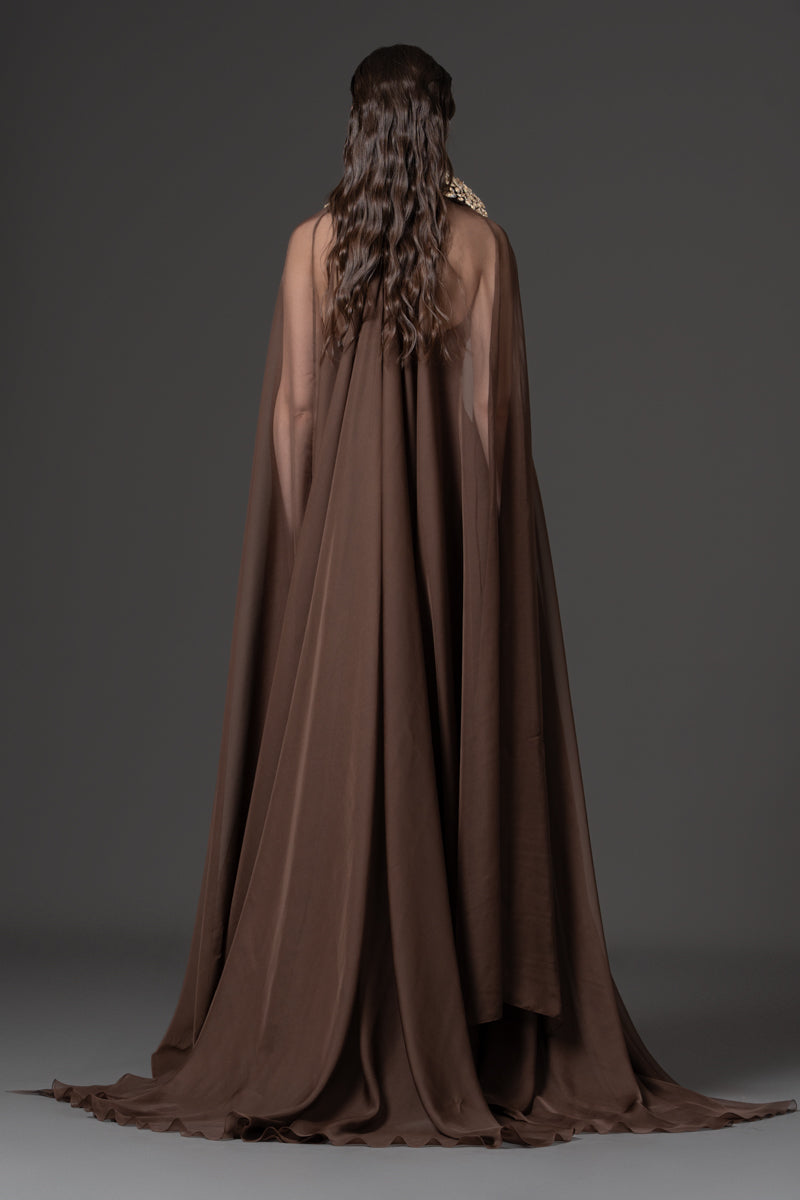 A fitted crêpe gown featuring chiffon cape and a beaded collar with crystals