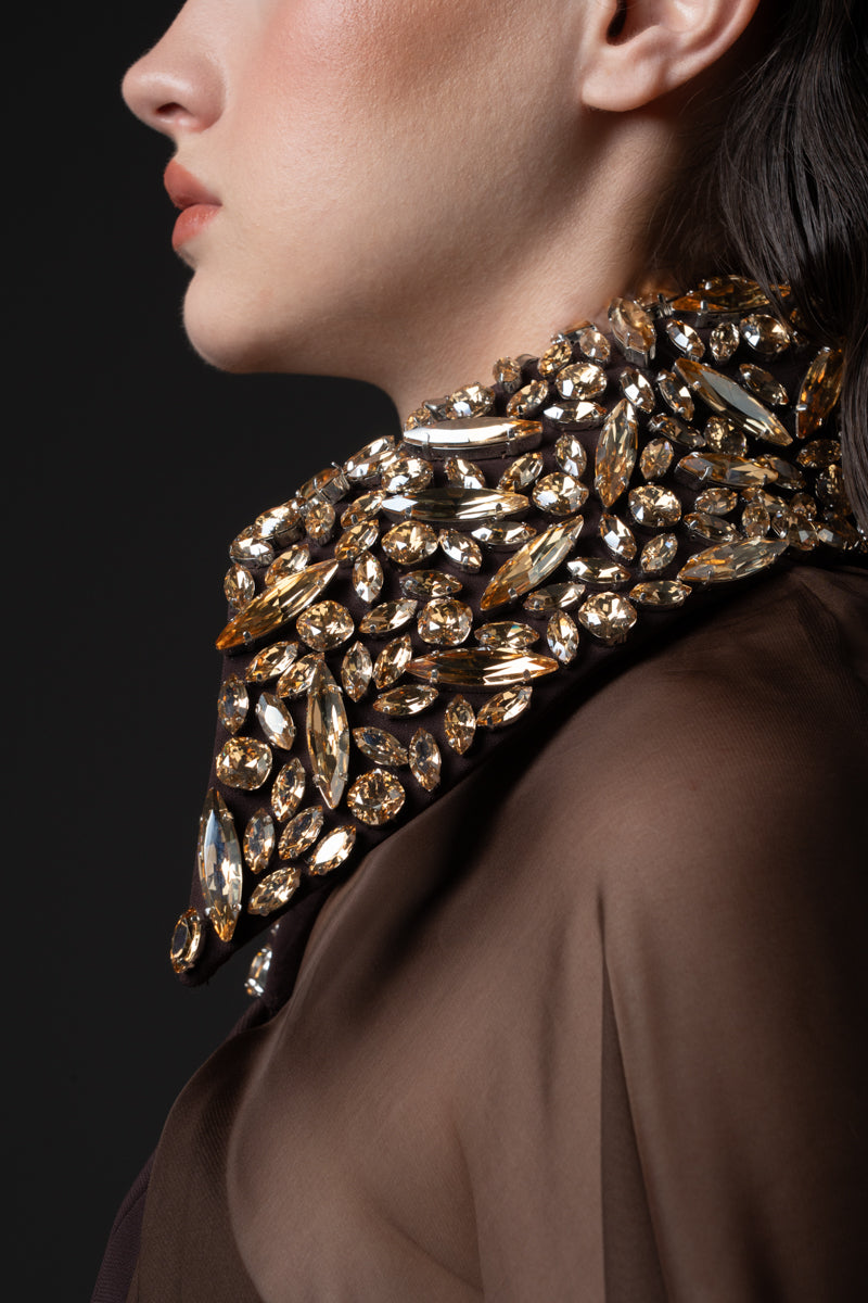 A fitted crêpe gown featuring chiffon cape and a beaded collar with crystals