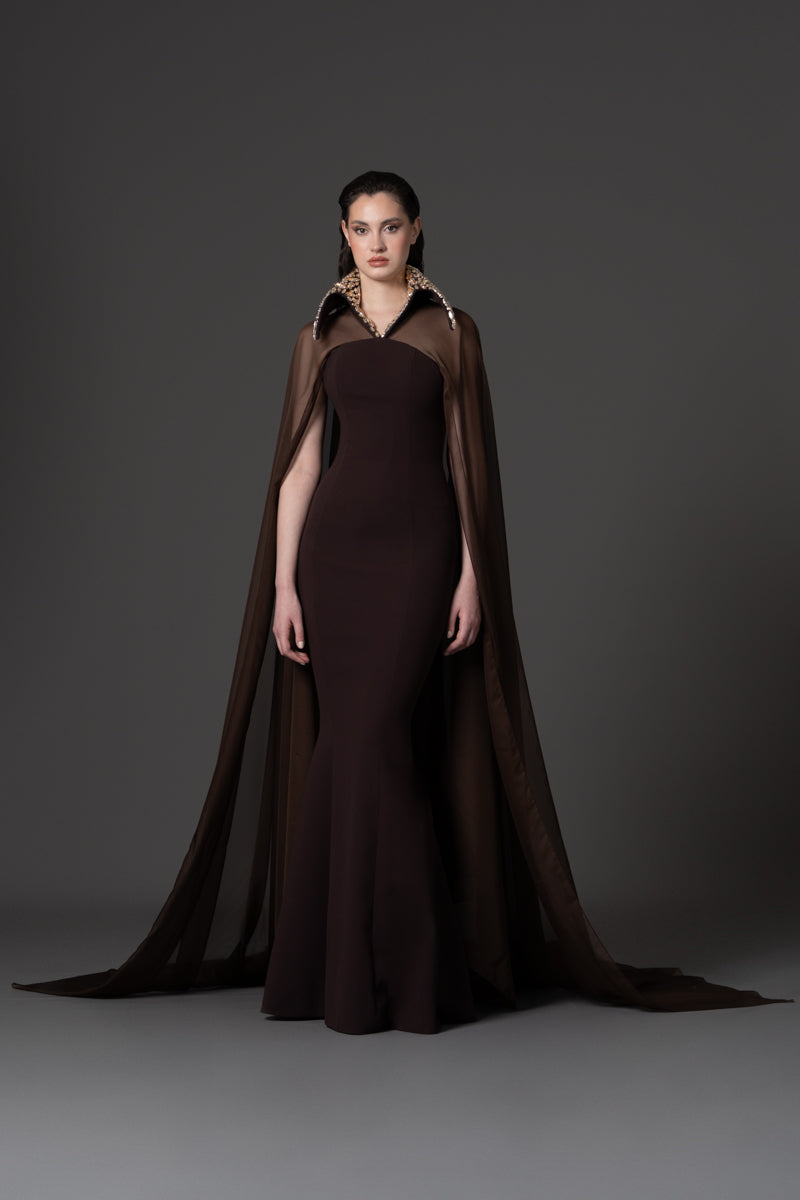A fitted crêpe gown featuring chiffon cape and a beaded collar with crystals