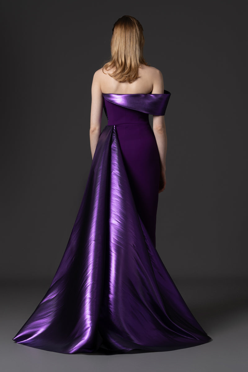 A fitted crêpe gown with a sculptural neckline layered with a voluminous asymmetrical lamé overskirt