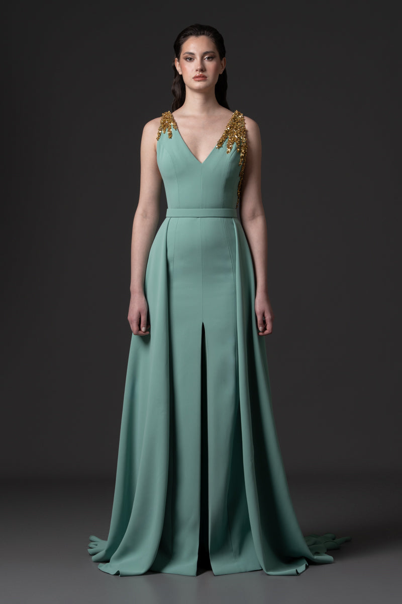 A fitted crêpe gown with an overskirt and sequins on shoulders