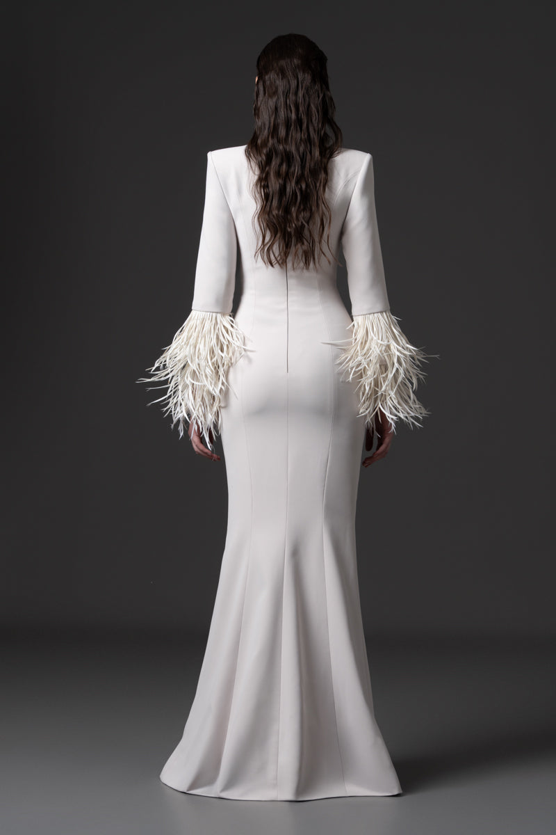 A fitted long sleeves dress with a beaded collar, a deep vertical opening at the bust and feathers on the sleeves