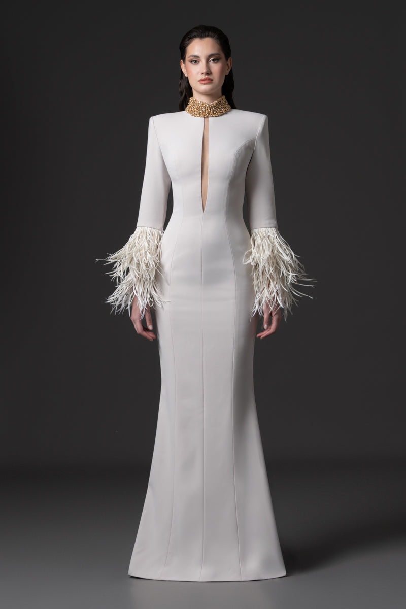 A fitted long sleeves dress with a beaded collar, a deep vertical opening at the bust and feathers on the sleeves