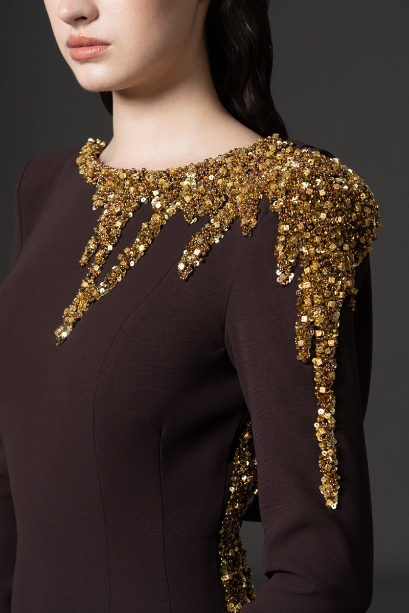 A long sleeves fitted crêpe gown with an open back and beaded with sequins