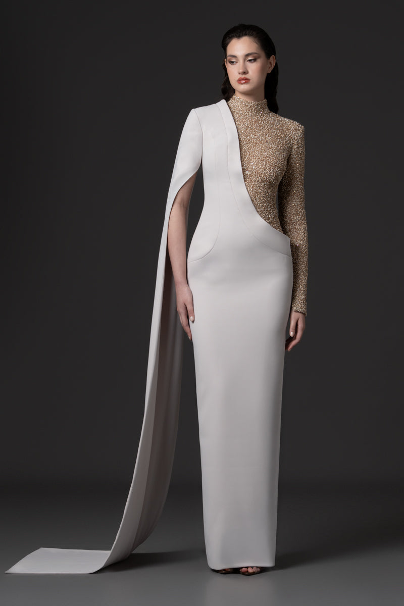 An asymmetric dress paired with a cape sleeve and an embroidered high- neck bodice