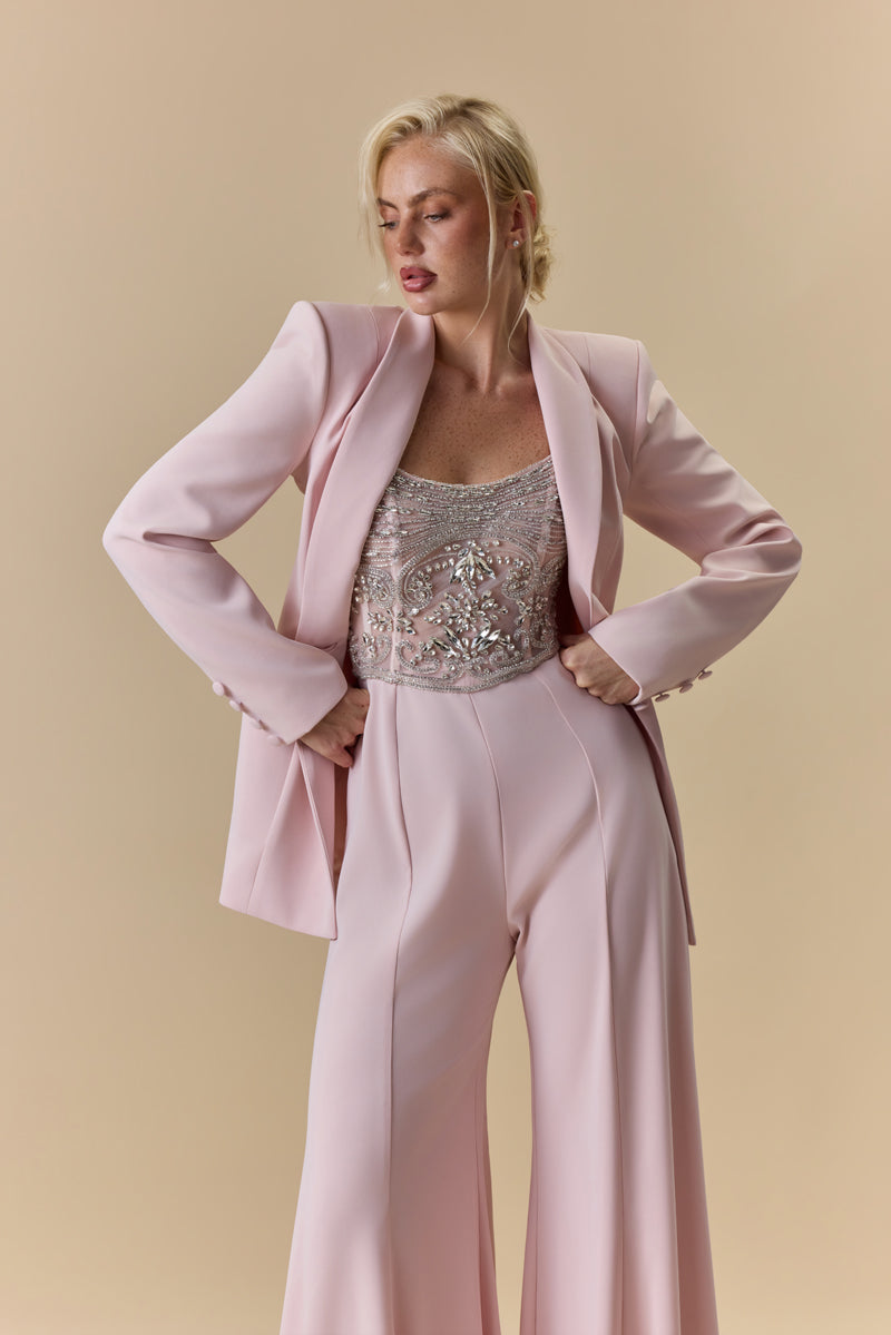 A strapless crêpe jumpsuit with an embroidered tulle corset embellished with crystals and stones, paired with a matching crêpe jacket.