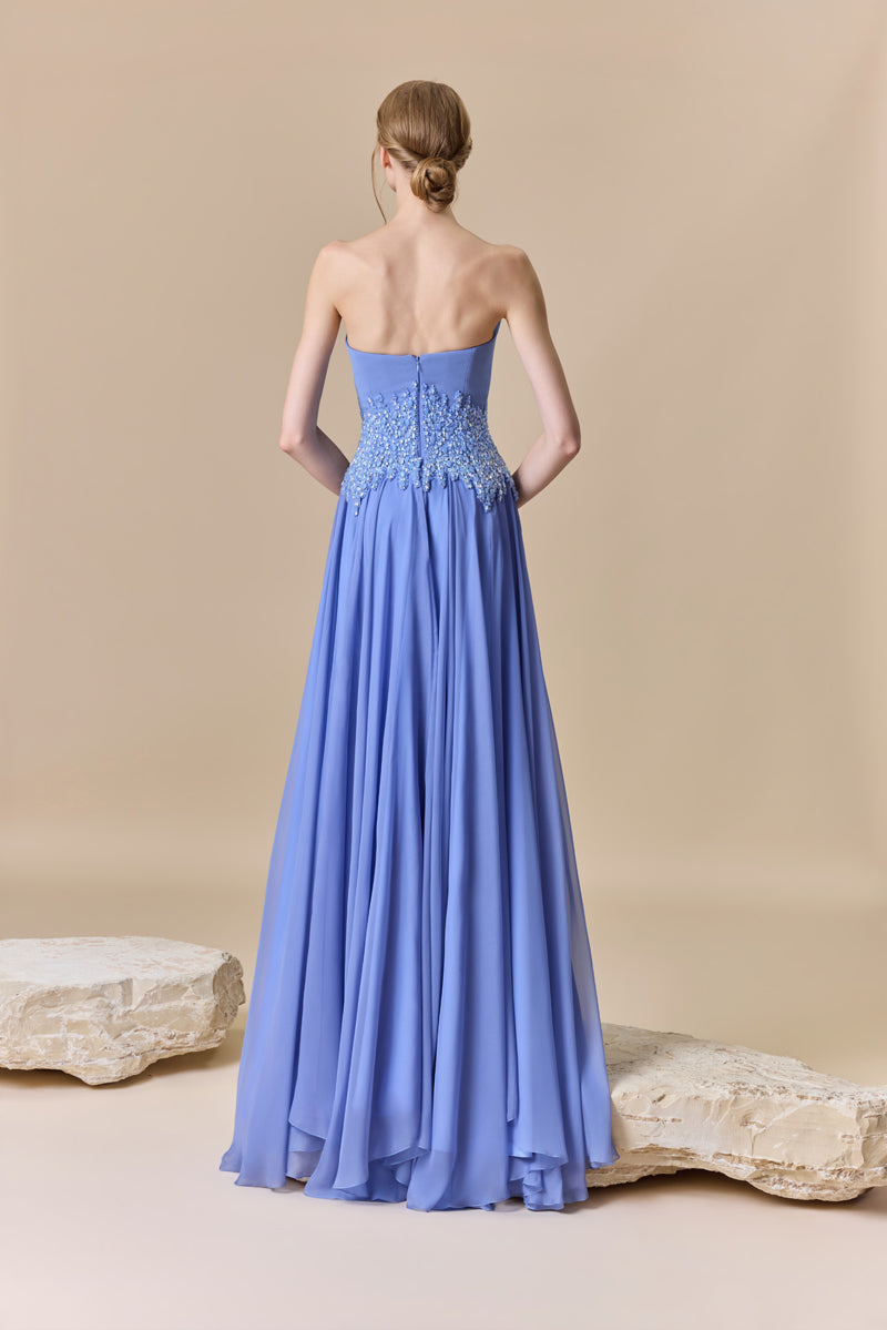 A strapless dress featuring a structured crepe bodice, a flowing chiffon skirt, and a crystal-beaded waist.