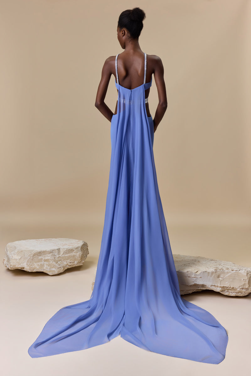 A fitted crepe dress featuring a halter neckline, side waist cutouts with a beaded belt, and a flowing chiffon cape attached at the back.