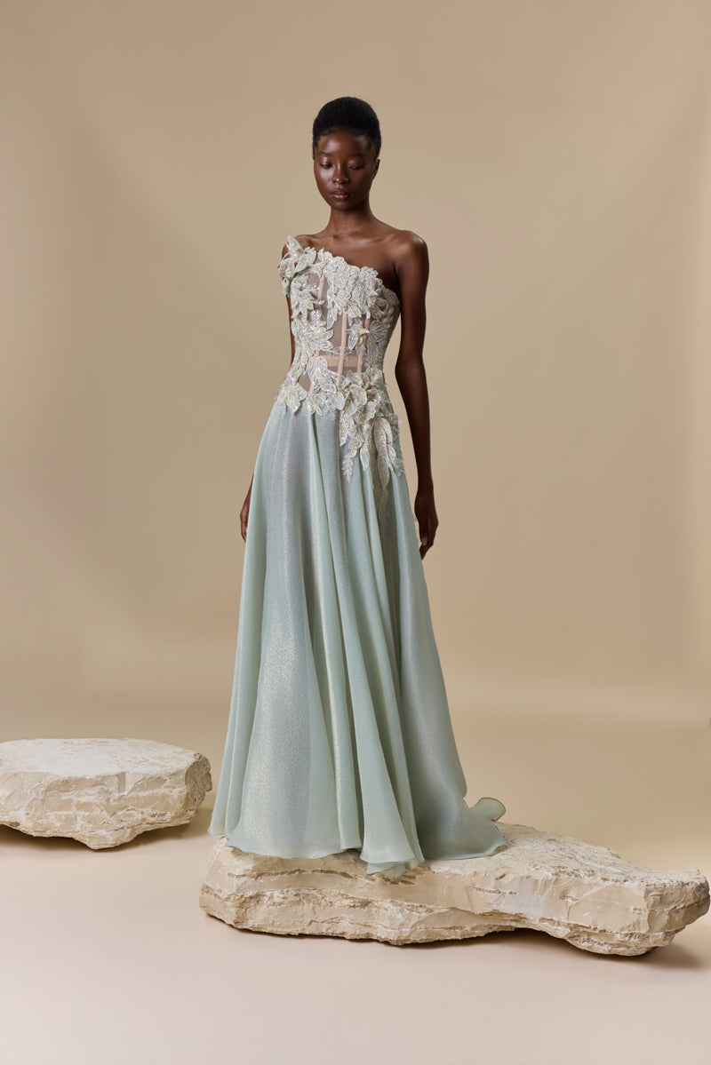 A strapless dress featuring an asymmetric bodice embellished with floral embroidery, paired with a flowing lame organza skirt.