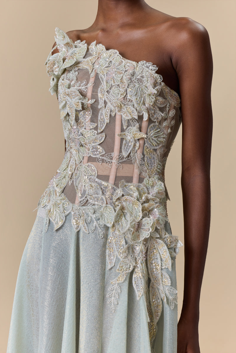 A strapless dress featuring an asymmetric bodice embellished with floral embroidery, paired with a flowing lame organza skirt.