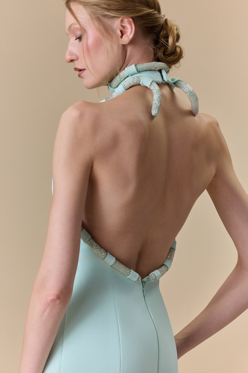 A fitted crepe halter-neck dress featuring beaded cords along the neckline and an open back.