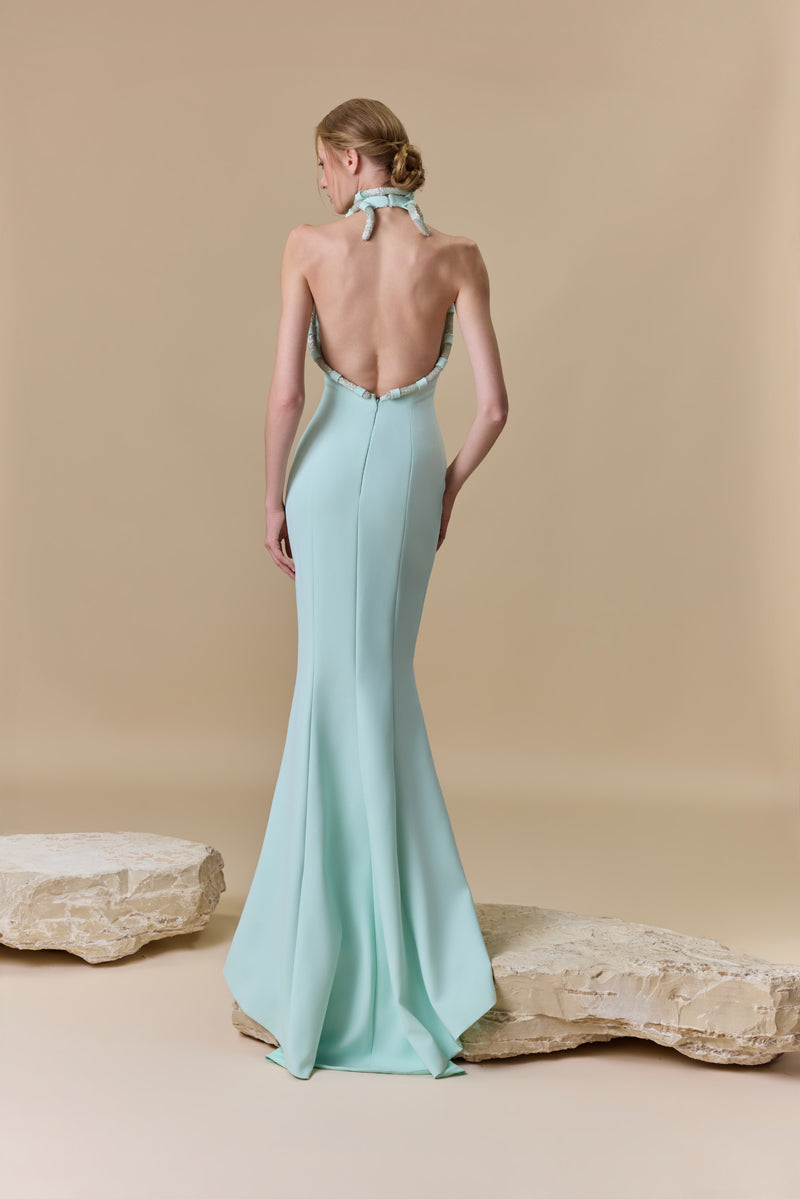 A fitted crepe halter-neck dress featuring beaded cords along the neckline and an open back.
