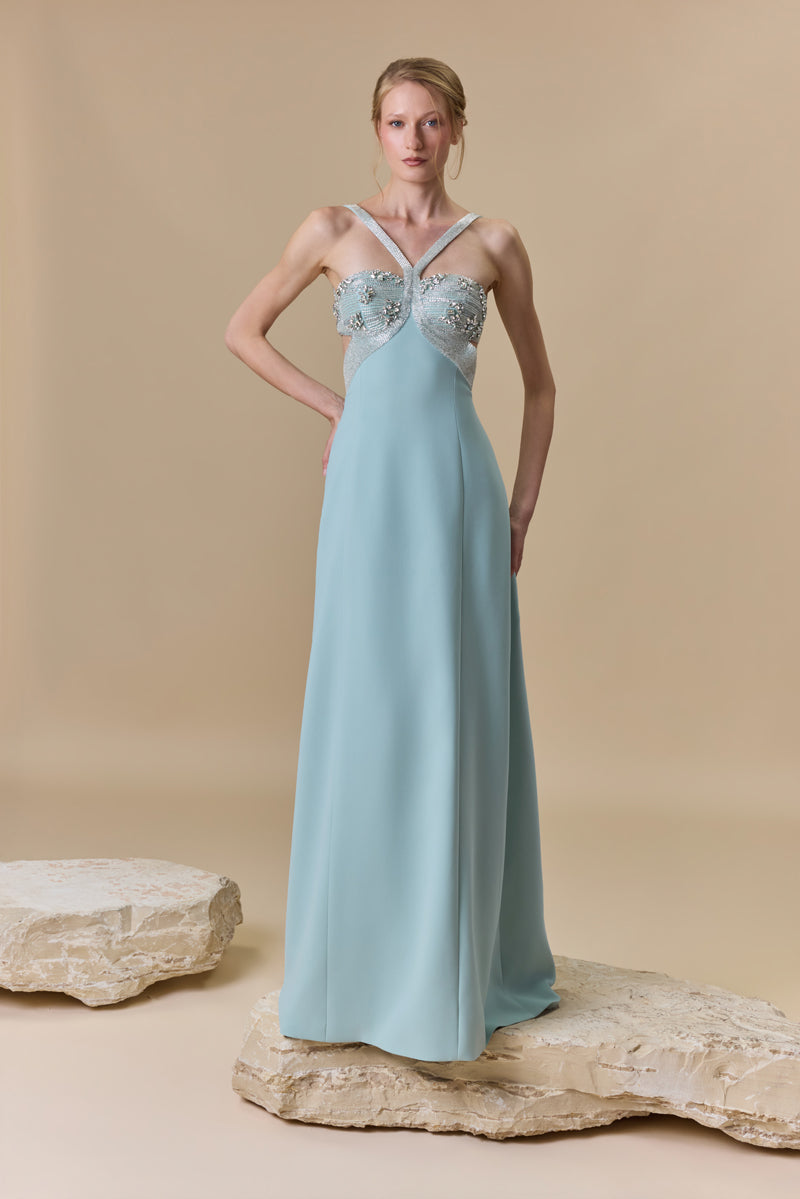 A straight crêpe dress featuring a crystal-beaded halter bust with a crossover neckline and a high side slit.