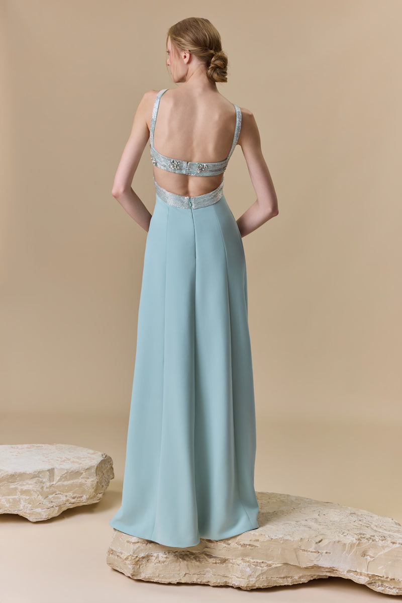 A straight crêpe dress featuring a crystal-beaded halter bust with a crossover neckline and a high side slit.
