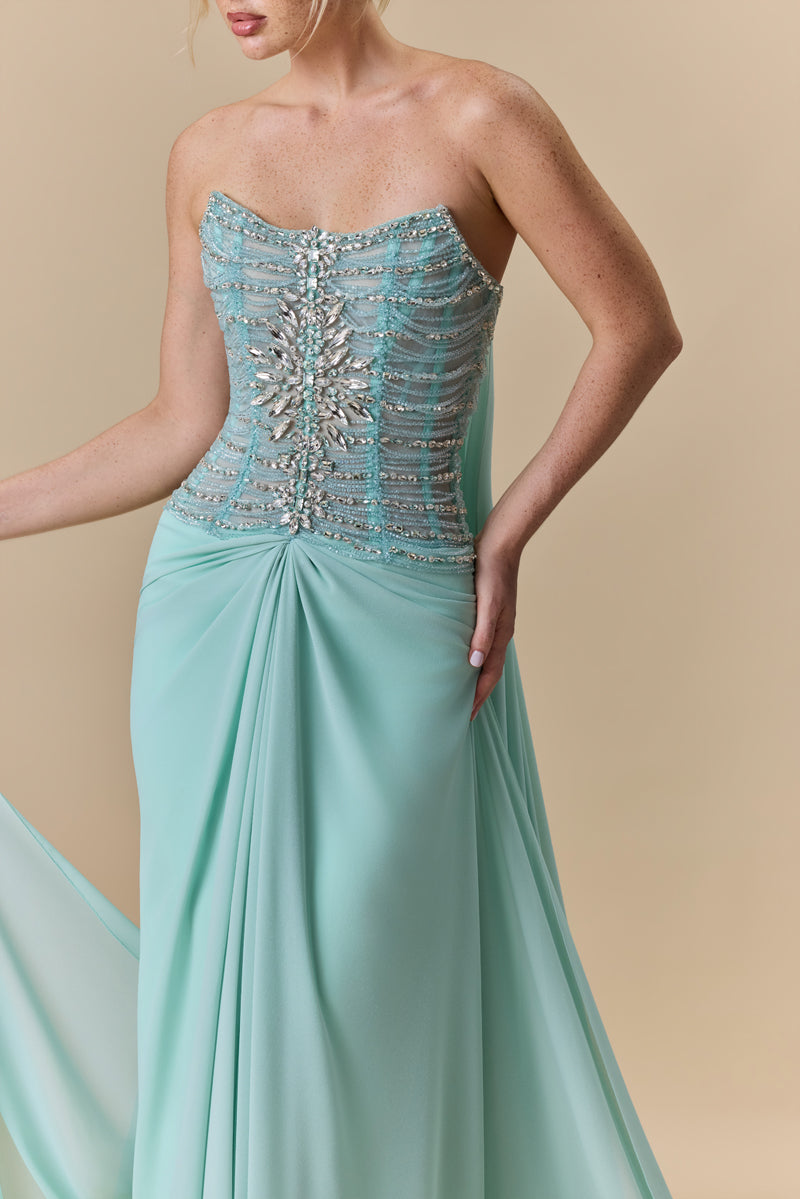 A strapless dress featuring a crystal-embellished corset bodice and a draped georgette skirt with a flowing back train.