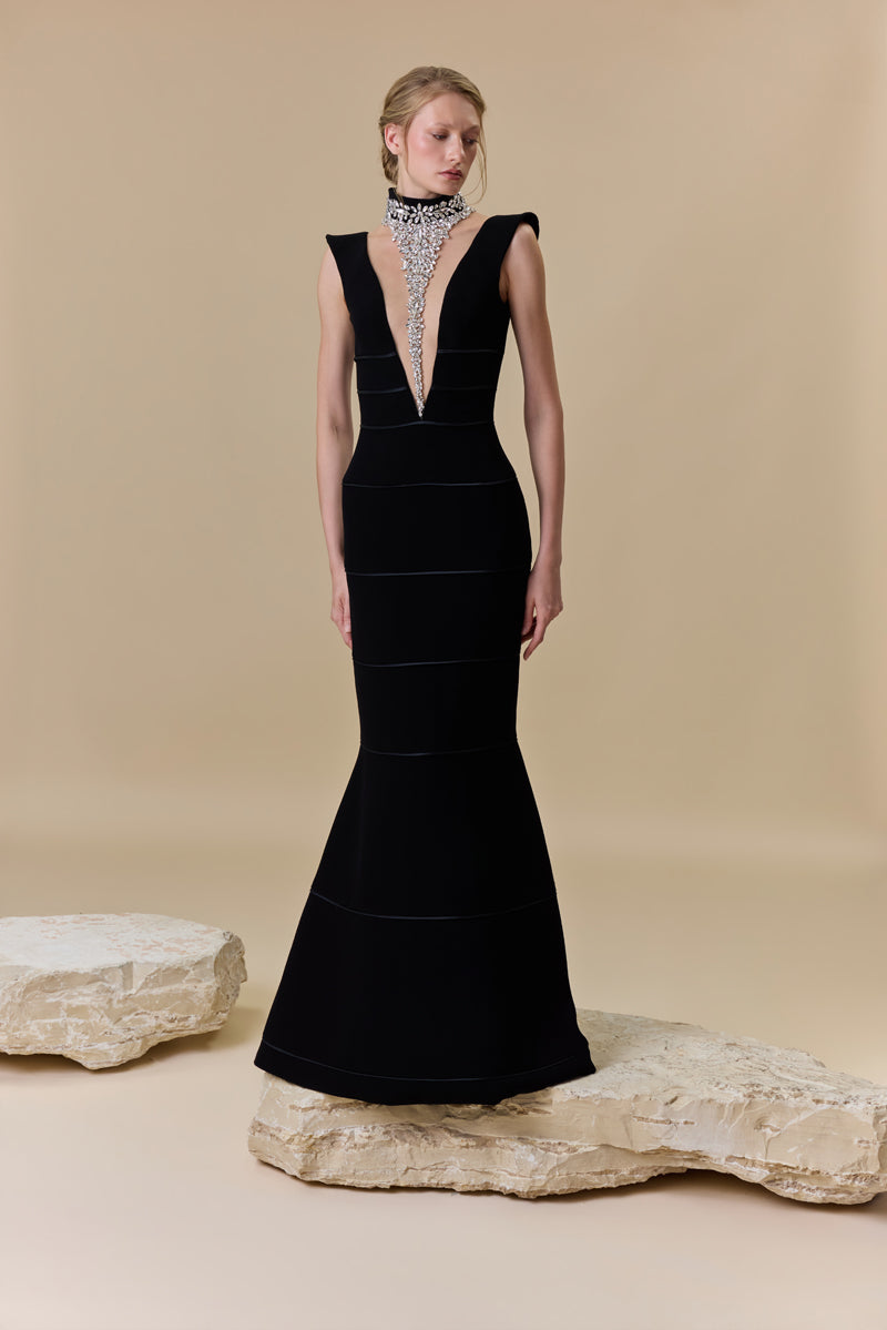 A crêpe fitted dress with a deep V neckline and horizontal radzimir detailing along the silhouette.