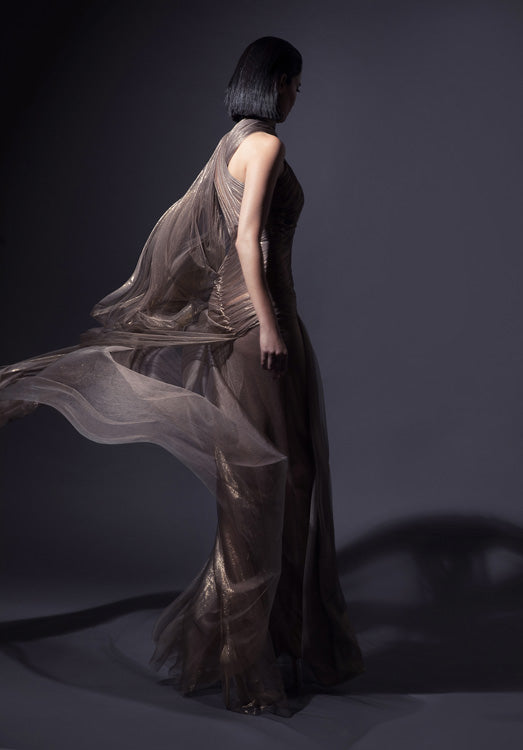 Asymmetrical halter gown with caped open sleeve in fairy-spun bronze foiled silk tulle