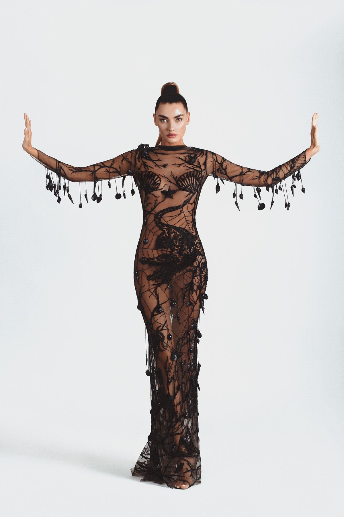 Seascape of sea creatures and underwater plant life embroidered onto a black tulle base and finished with hanging clams and shells