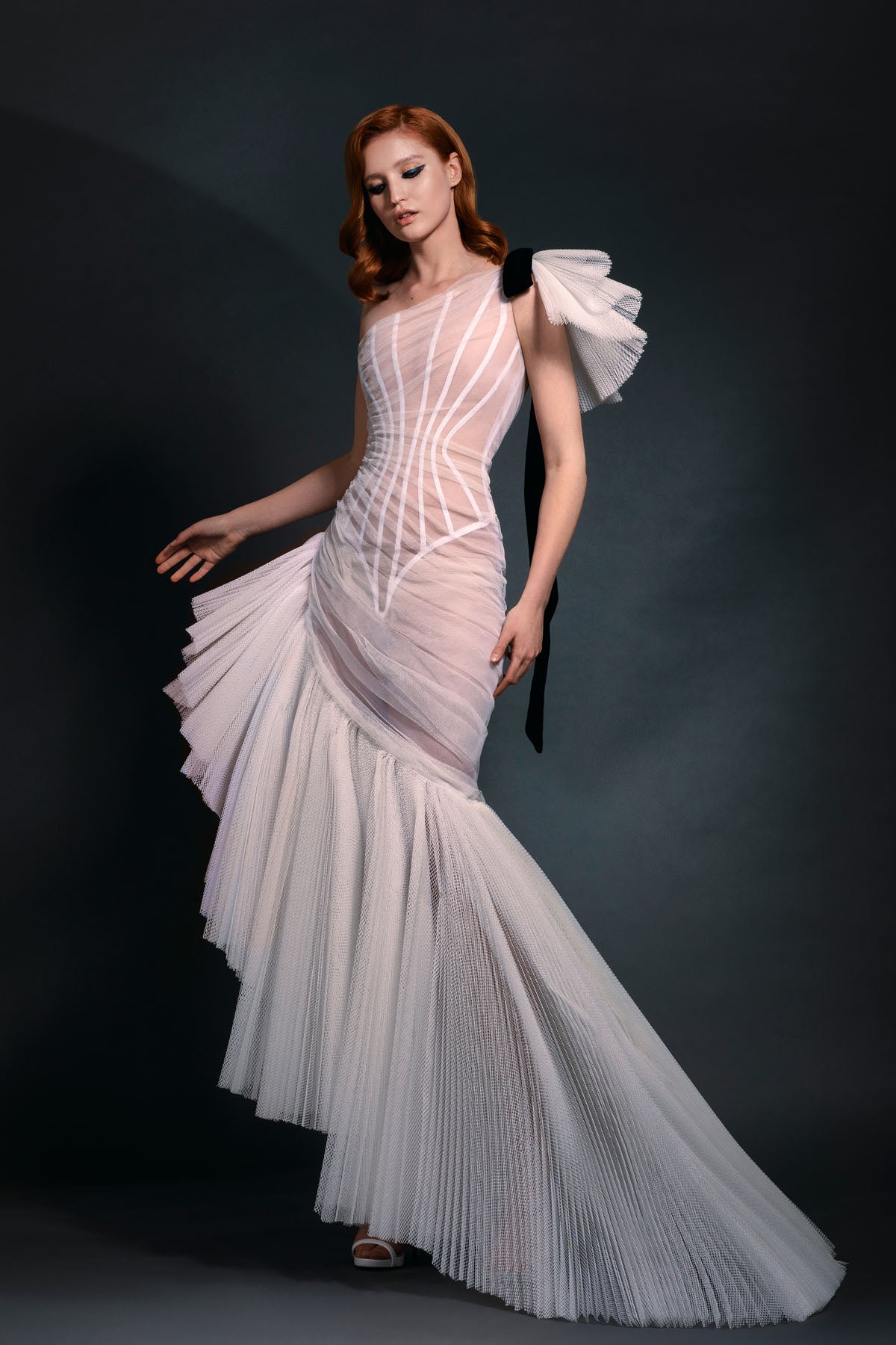 Sleeveless asymmetrical ivory pleated tulle gown with black velvet bow detailing
