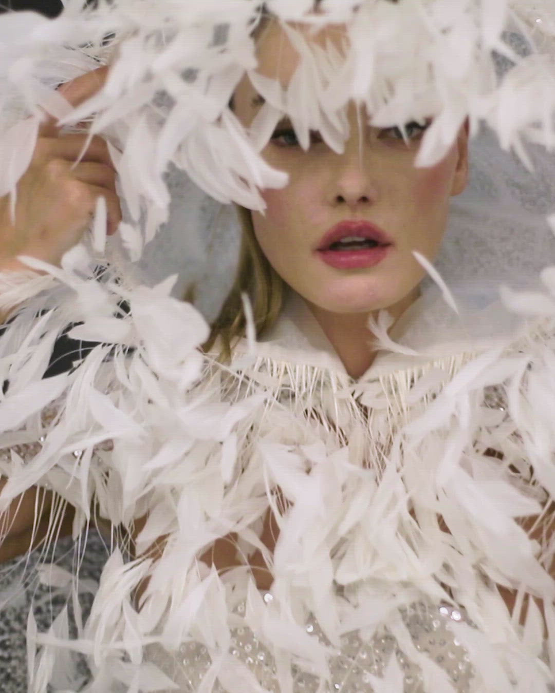 Metallic silver threads, glass beads and sequins embroidered white tulle strapless gown worn with a hooded cape, hand appliquéd with coq plumes