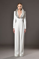 Long sleeved white crêpe jumpsuit with structured shoulders and feathers embroidered collar