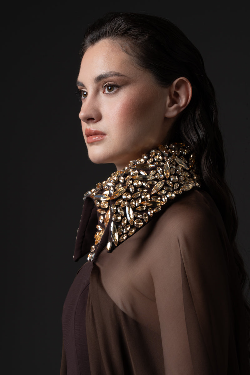 A fitted crêpe gown featuring chiffon cape and a beaded collar with  crystals