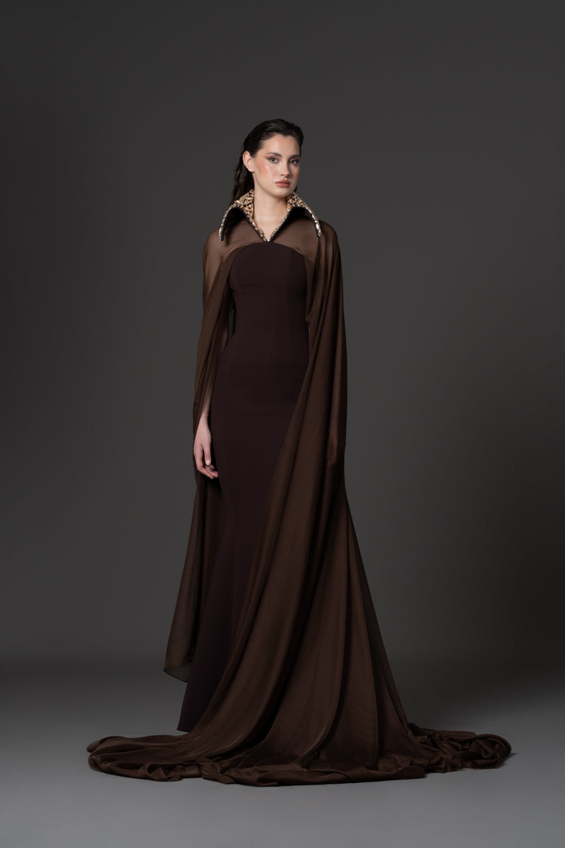 A fitted crêpe gown featuring chiffon cape and a beaded collar with  crystals
