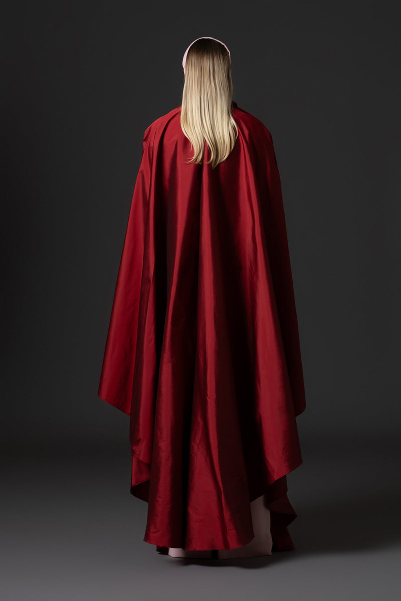 Pink crêpe abaya paired with a red taffeta cape