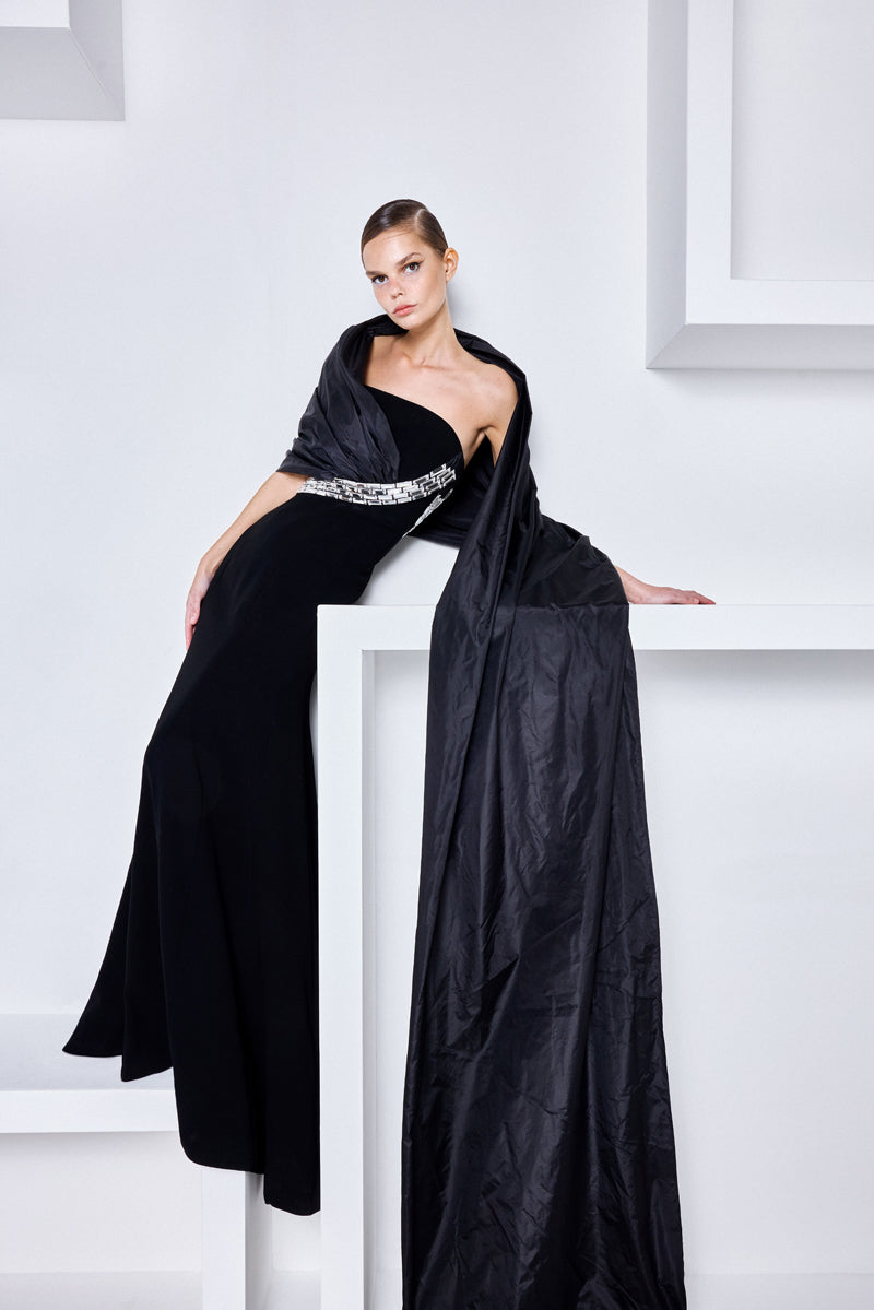 A strapless crepe gown with an elegant off-the-shoulder taffeta drape and baguette stones at the waist