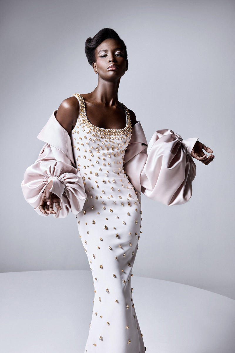 A fitted round neckline crêpe gown beaded with navette stones with a radzimir bomber jacket