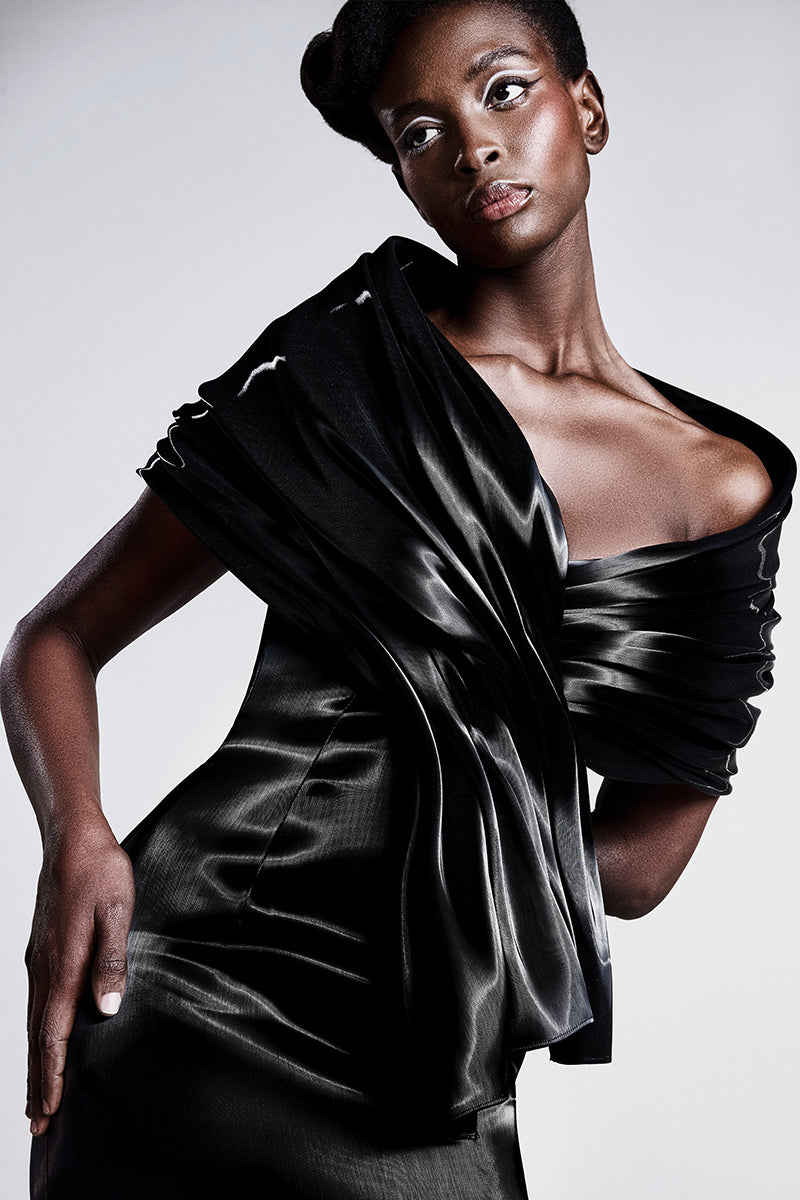 An off-shoulder liquid gazar dress with sculptural draping on the bust