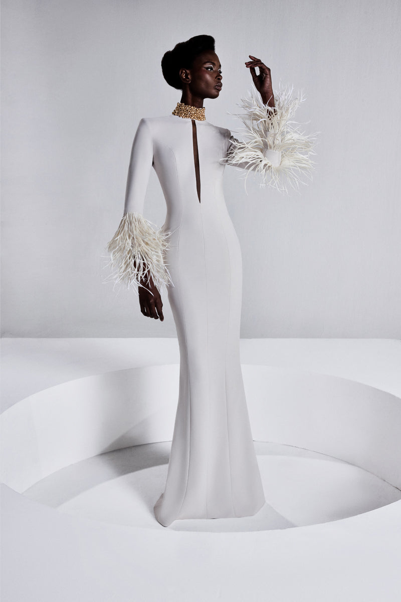 A fitted long sleeves dress with a beaded collar, a deep vertical opening  at the bust and feathers on the sleeves