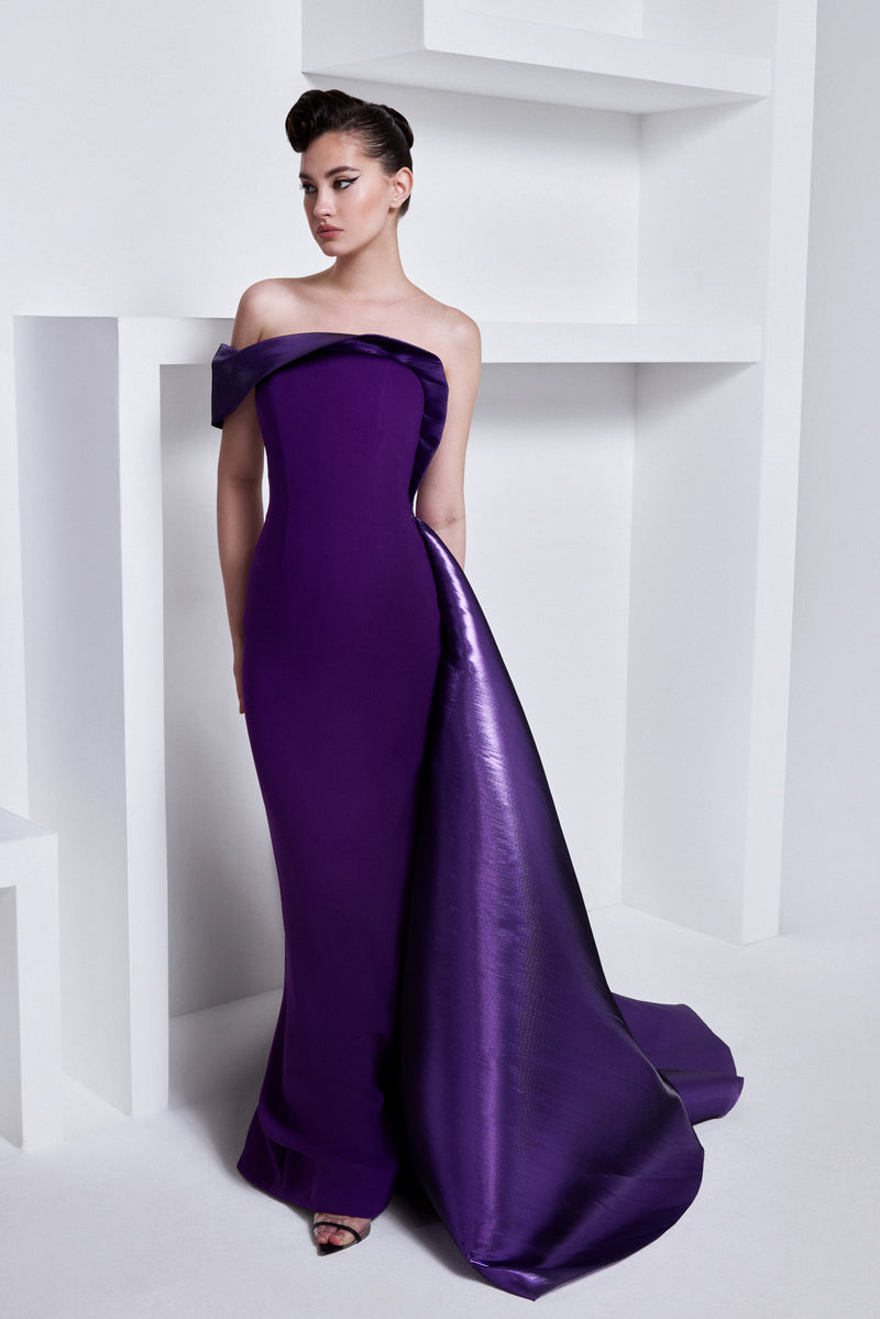 A fitted crêpe gown with a sculptural neckline layered with a  voluminous  asymmetrical lamé overskirt