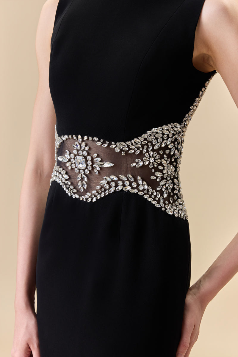 A crêpe fitted dress with an open back, a train at the back, and crystal detailing along the neckline, waist, and back borders.