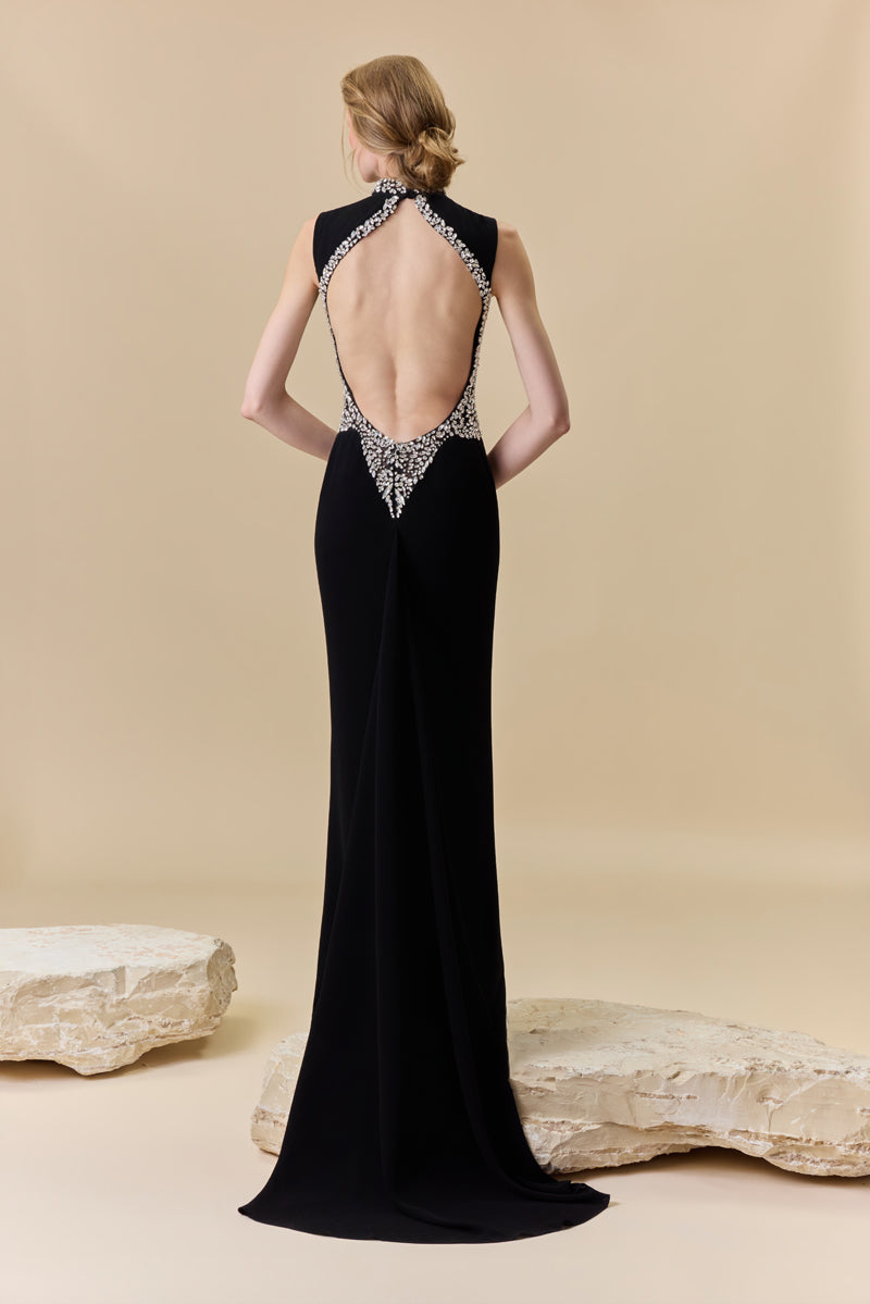 A crêpe fitted dress with an open back, a train at the back, and crystal detailing along the neckline, waist, and back borders.