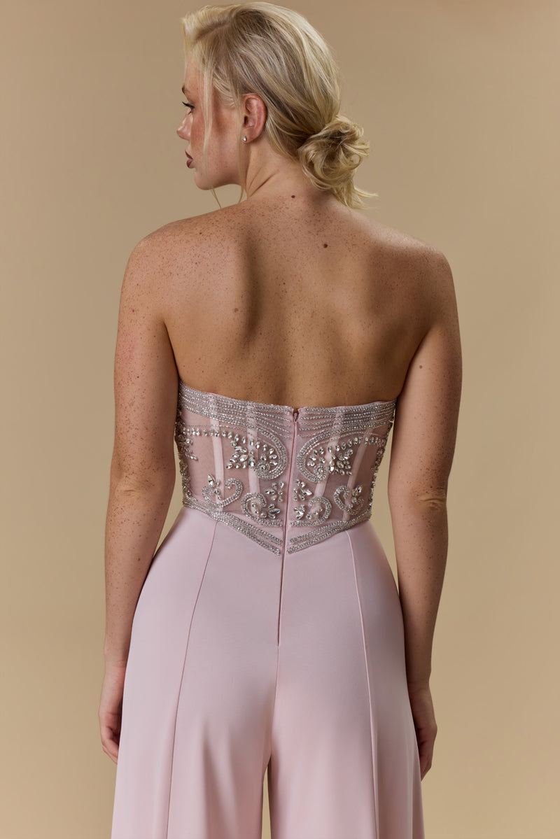 A strapless crêpe jumpsuit with an embroidered tulle corset embellished with crystals and stones, paired with a matching crêpe jacket.