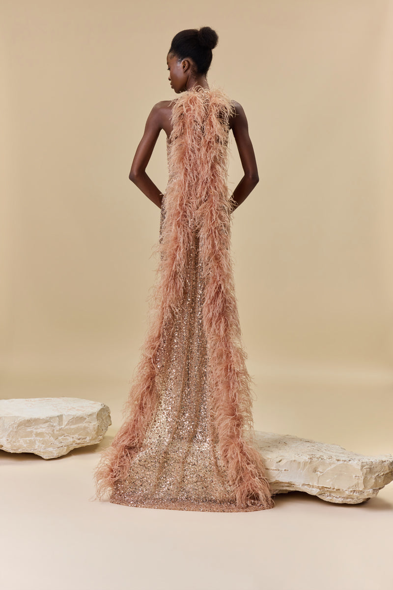 A fitted embroidered tulle dress with a halter neckline, open back, and a dramatic flowing train finished with feather trims.