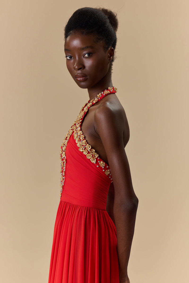 A georgette halter-neck dress embellished with metallic flowers and crystals neckline, waist draping, an open back, and a flowing A-line skirt.