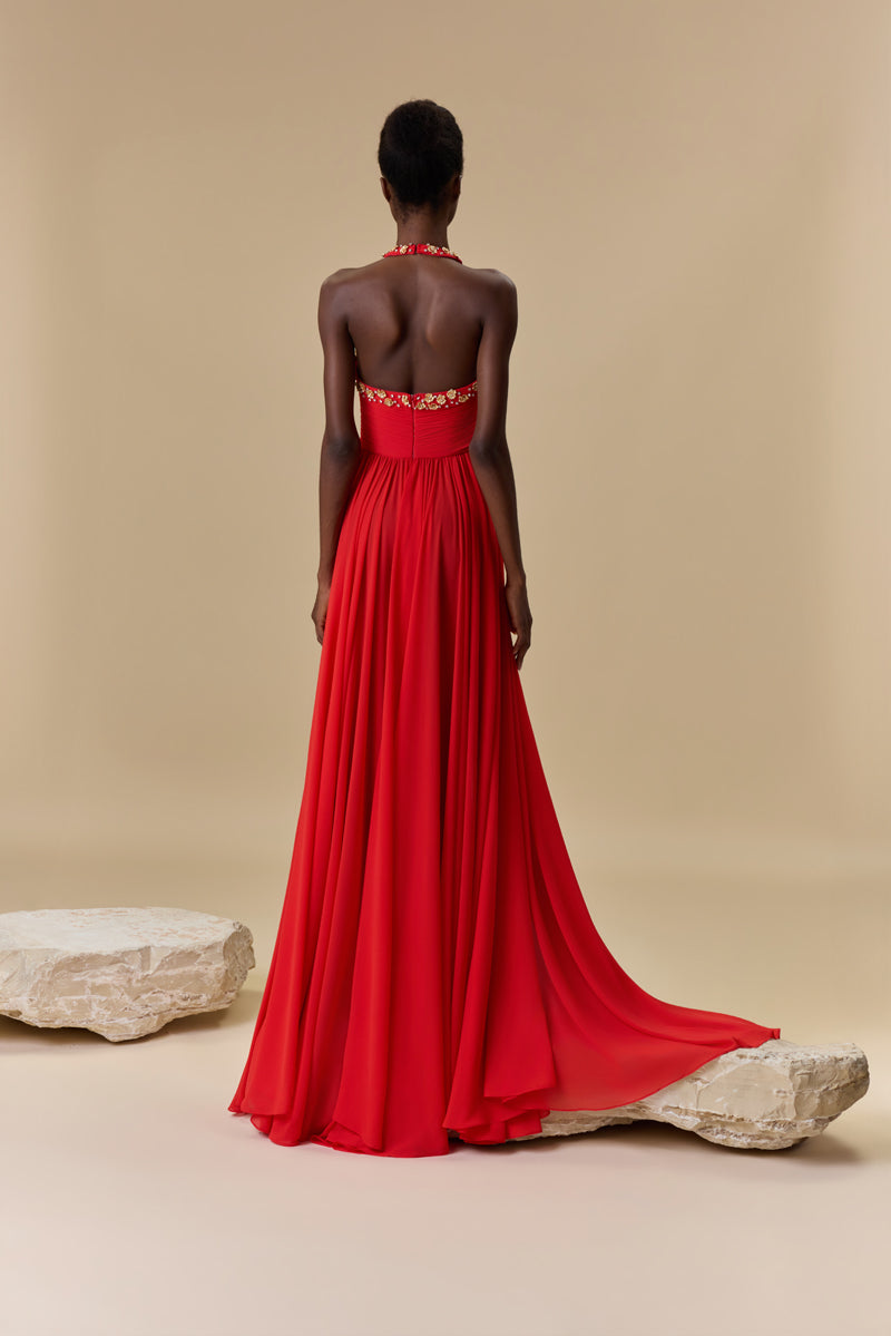 A georgette halter-neck dress embellished with metallic flowers and crystals neckline, waist draping, an open back, and a flowing A-line skirt.