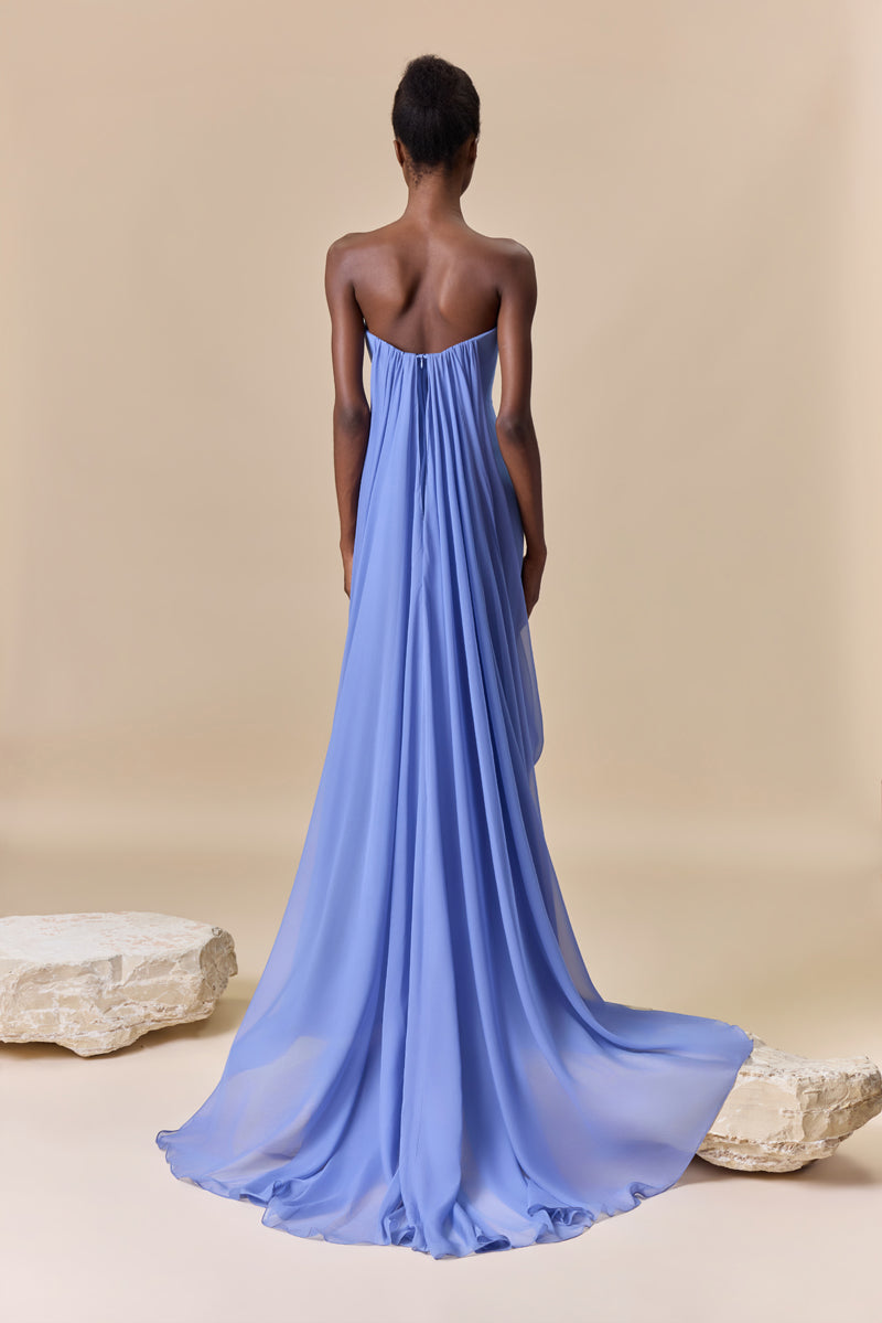 A strapless fitted crêpe dress featuring a straight neckline embellished with crystals with long, cascading chiffon drapes attached to the bodice.