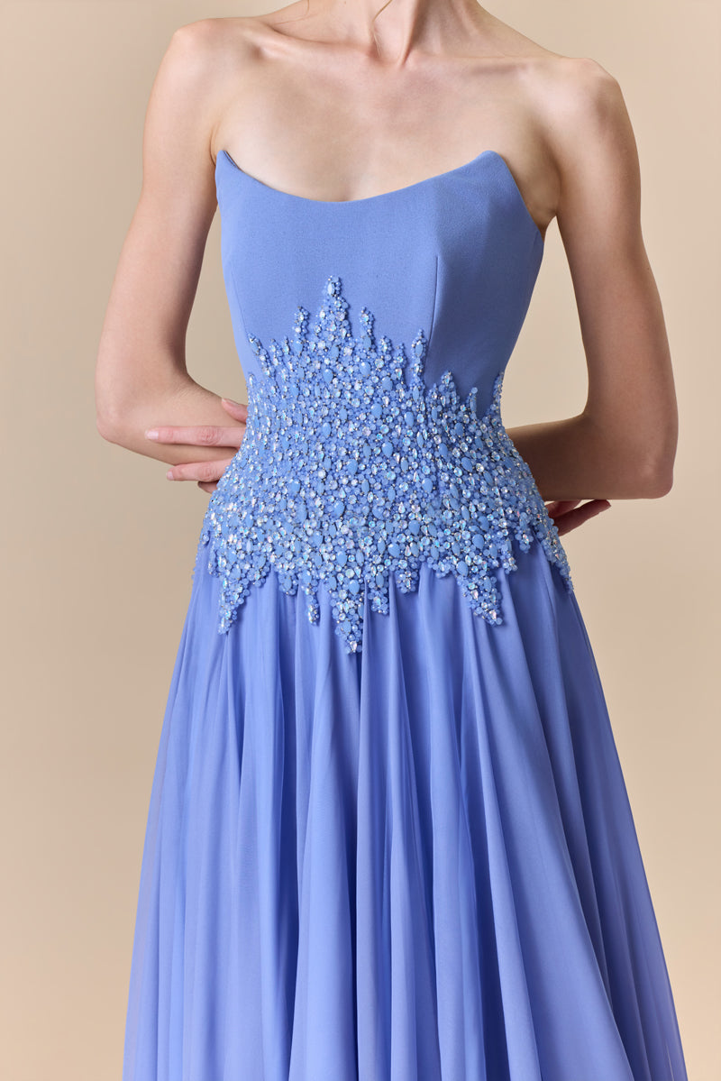 A strapless dress featuring a structured crepe bodice, a flowing chiffon skirt, and a crystal-beaded waist.