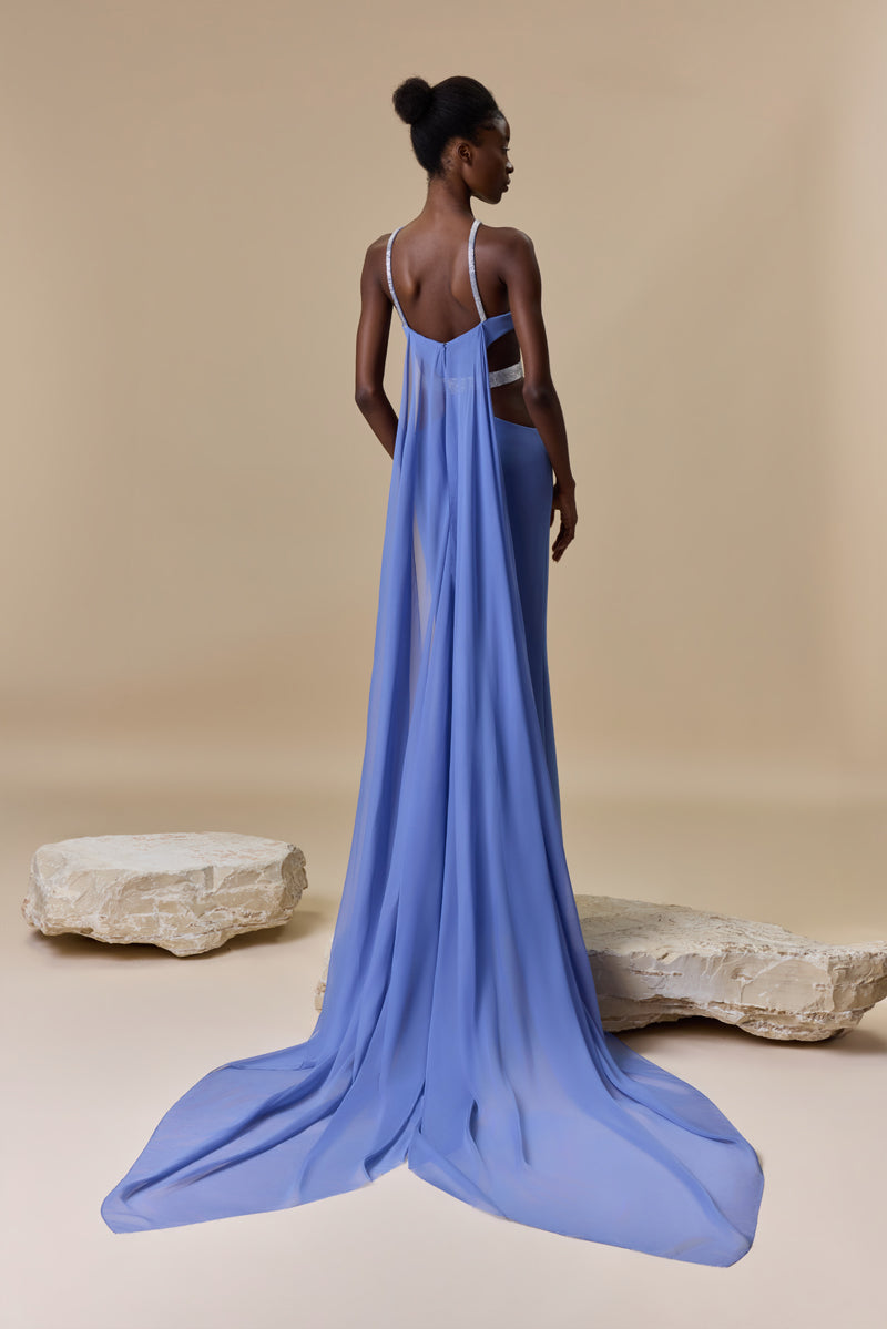 A fitted crepe dress featuring a halter neckline, side waist cutouts with a beaded belt, and a flowing chiffon cape attached at the back.