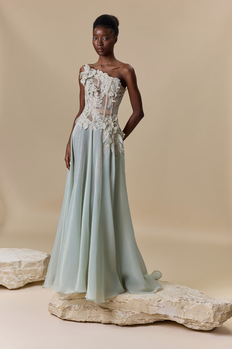 A strapless dress featuring an asymmetric bodice embellished with floral embroidery, paired with a flowing lame organza skirt.