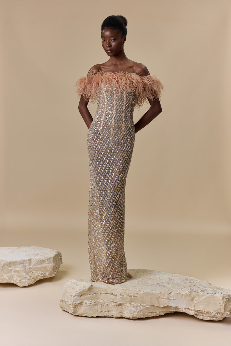 A strapless fitted dress fully beaded with crystals and finished with an off-shoulder feather trimmed neckline.