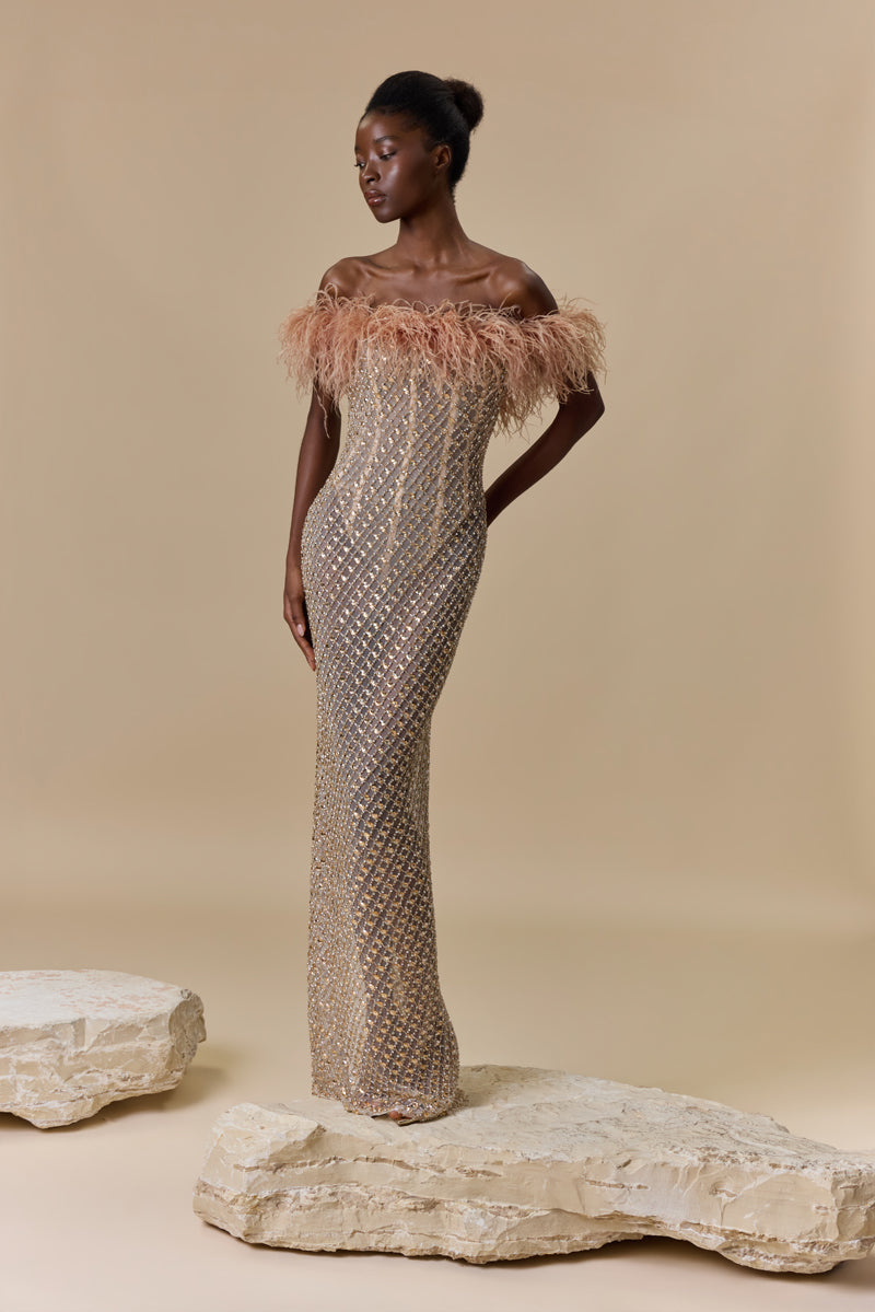 A strapless fitted dress fully beaded with crystals and finished with an off-shoulder feather trimmed neckline.
