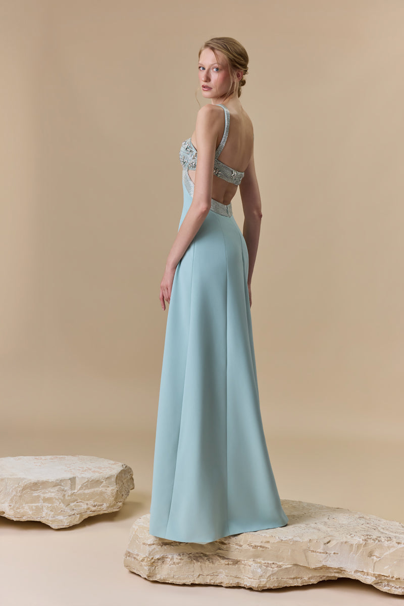 A straight crêpe dress featuring a crystal-beaded halter bust with a crossover neckline and a high side slit.