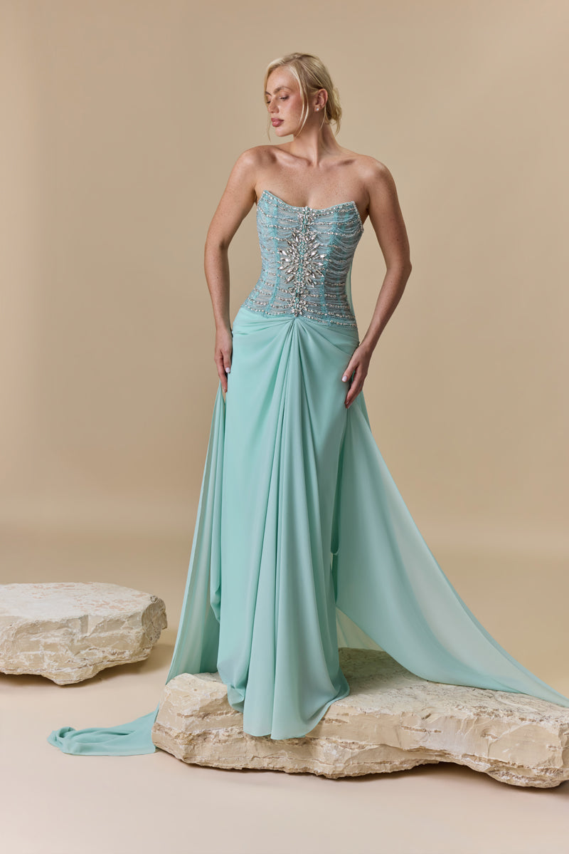 A strapless dress featuring a crystal-embellished corset bodice and a draped georgette skirt with a flowing back train.